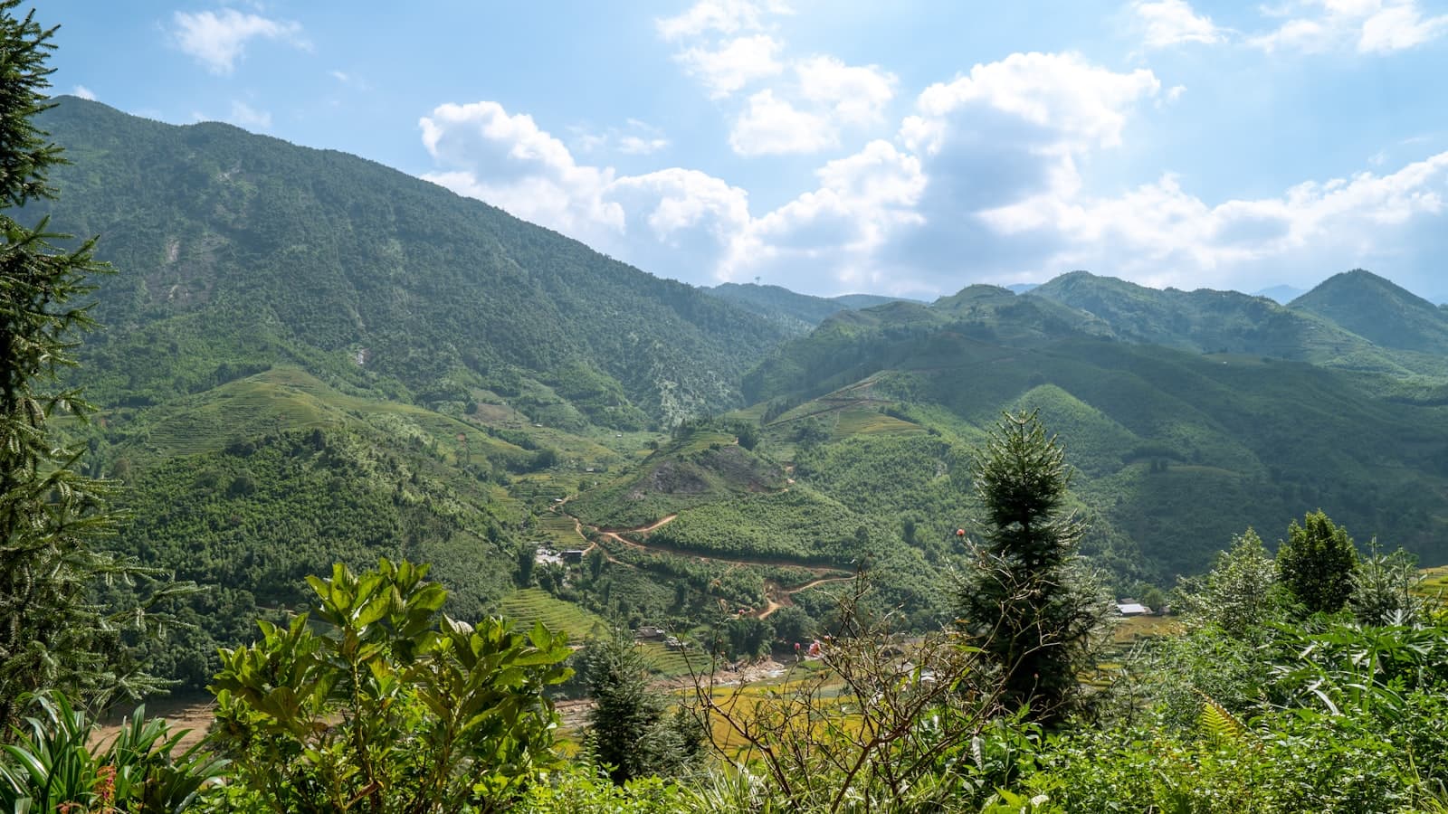 Green mountain valley near Sapa under a bright sky, terraced fields in the distance