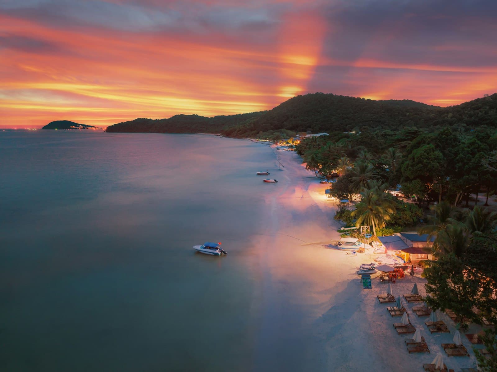 Quiet beach in Phu Quoc with palm trees leaning over soft white sand at sunset
