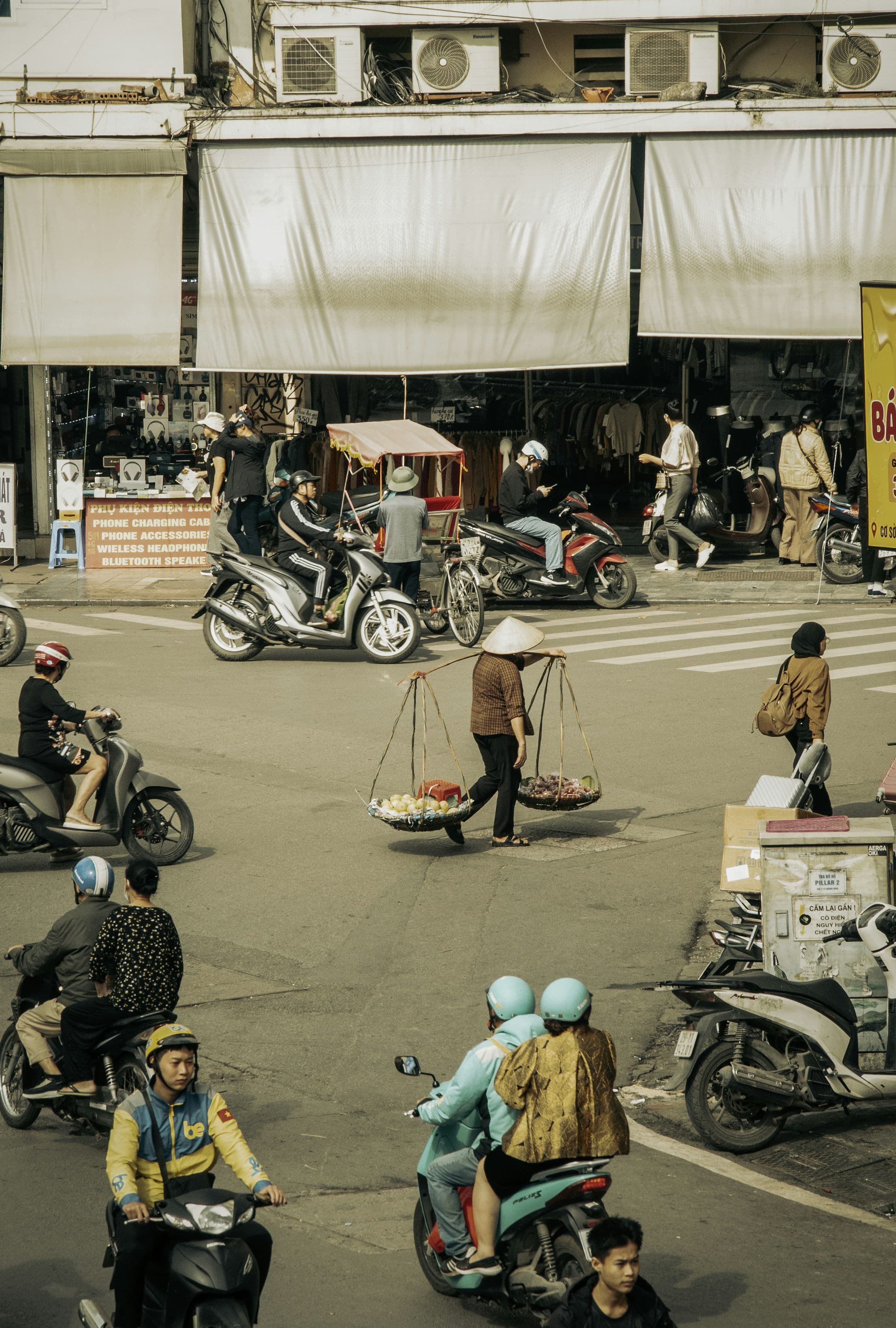 Motorbikes flowing down a wide Saigon boulevard at golden hour, towers rising behind